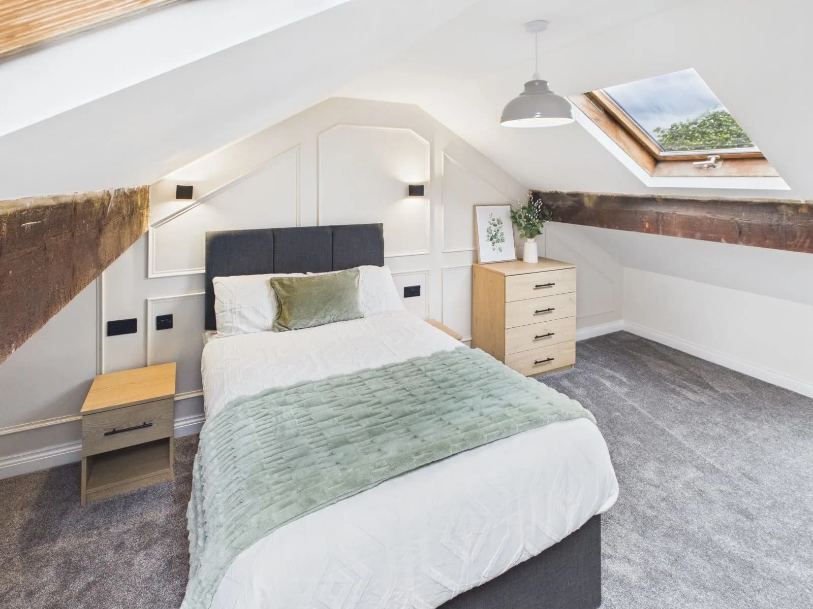 Loft-level bedroom with sloped ceiling, exposed timber beam and a rooflight at the completed Darlington HMO.