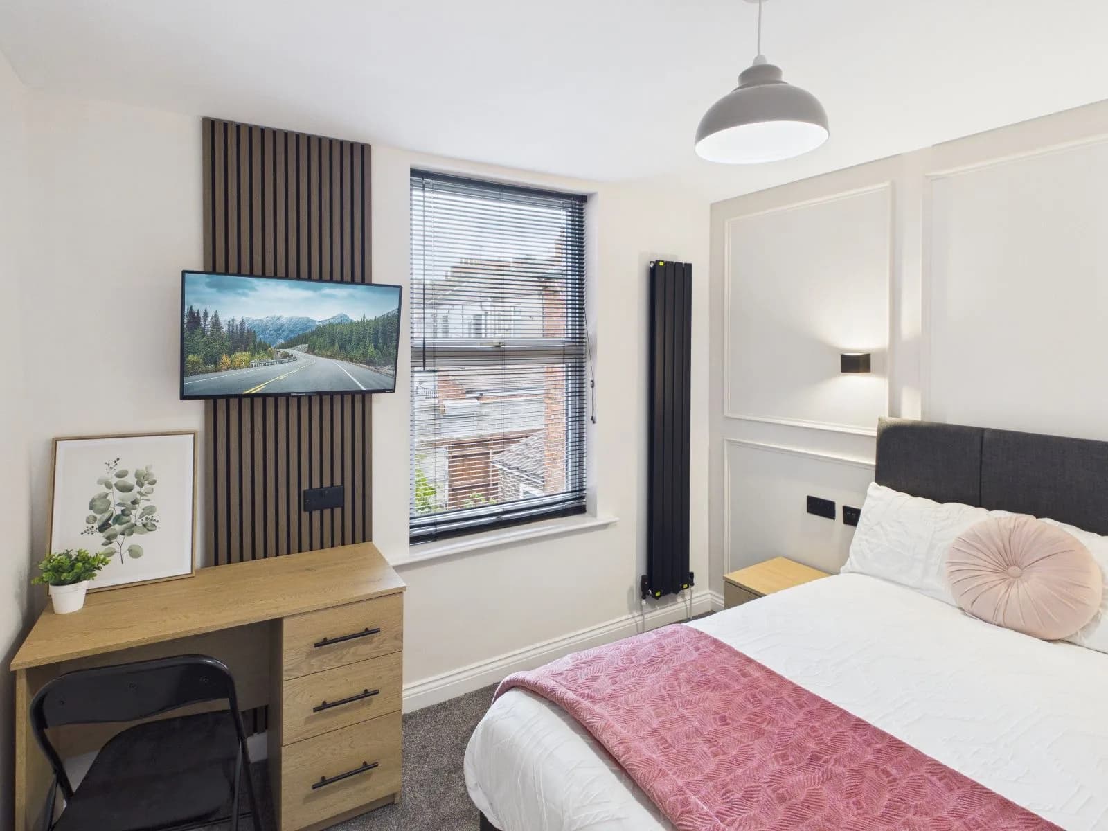 Bedroom with a wall-mounted television on slatted panelling and a desk at the completed Darlington HMO.