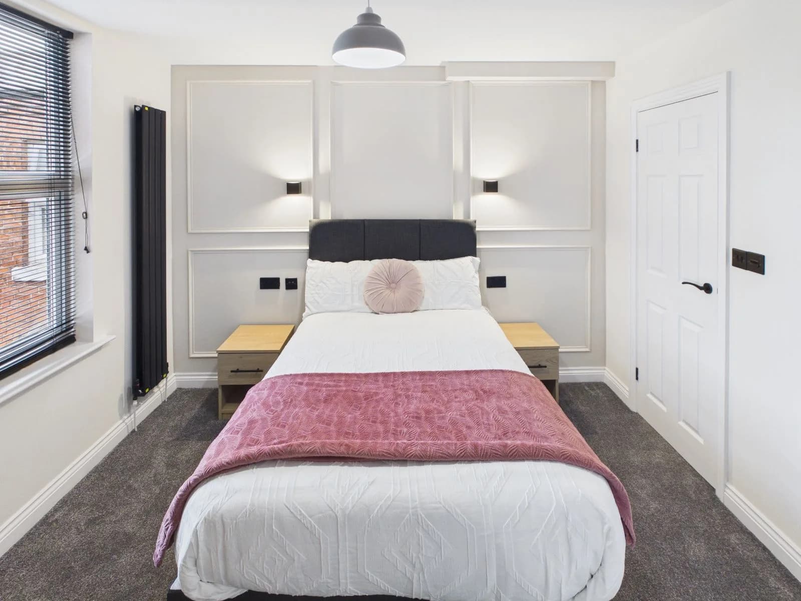 Bedroom with a panelled headboard wall, wall lights and twin bedside tables at the completed Darlington HMO.
