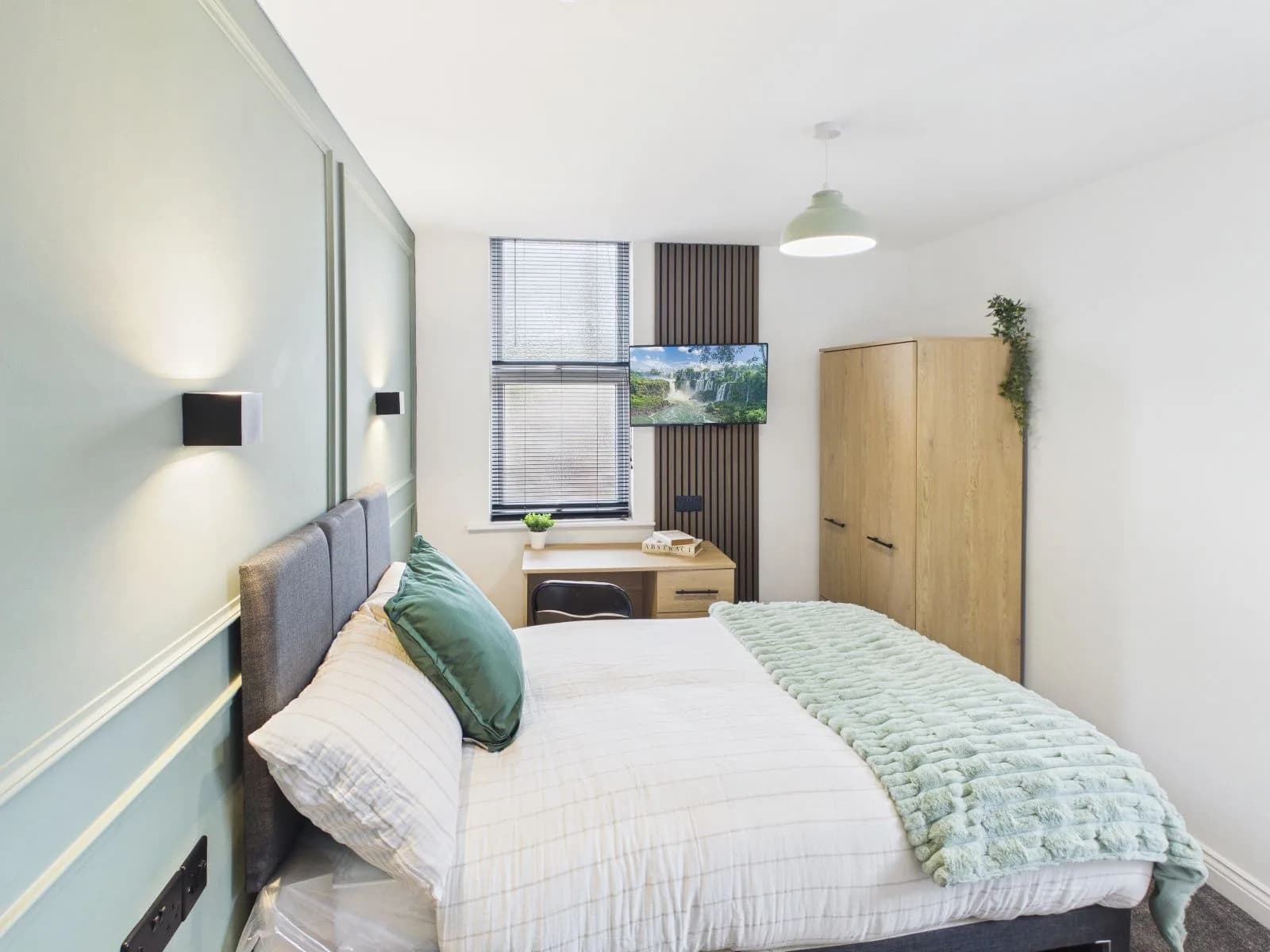 Bedroom with a painted green panelled wall, desk and wardrobe at the completed Darlington HMO.