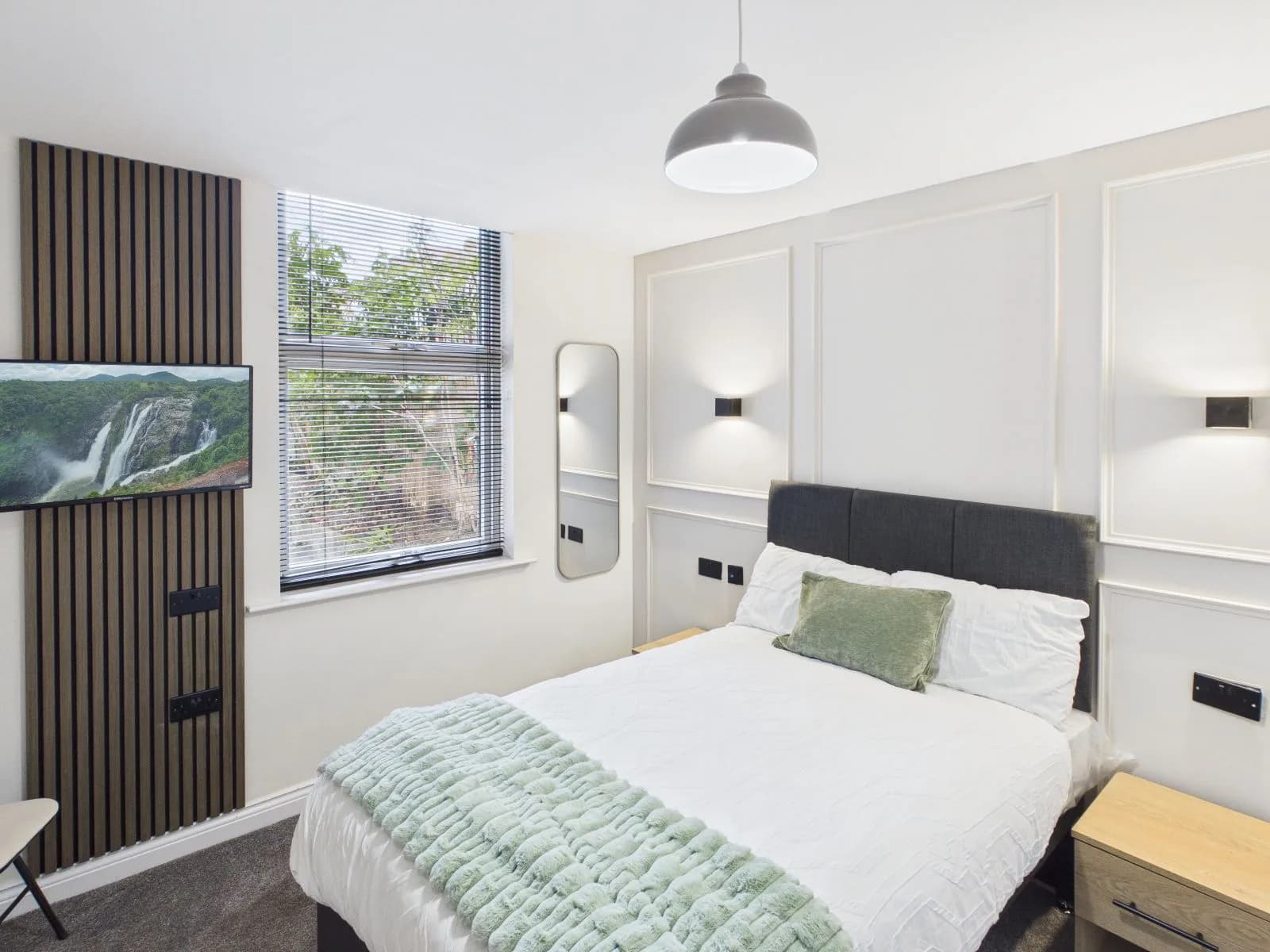 Bedroom with a wall-mounted television on slatted panelling and wall lights at the completed Darlington HMO.