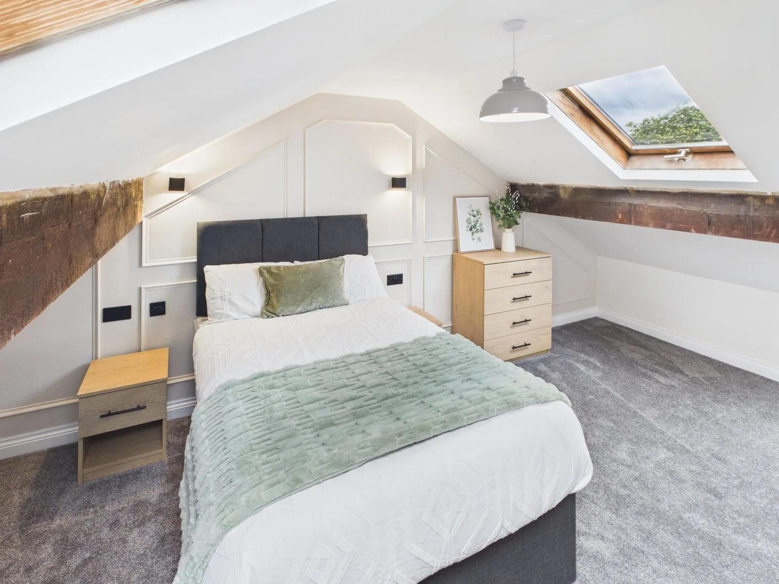 Loft-level bedroom with sloped ceiling, exposed timber beam and a rooflight at the completed Darlington HMO.